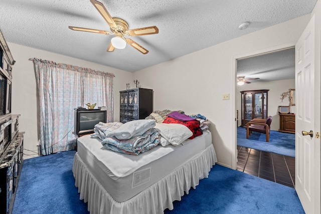 bedroom with a textured ceiling, ceiling fan, and dark carpet