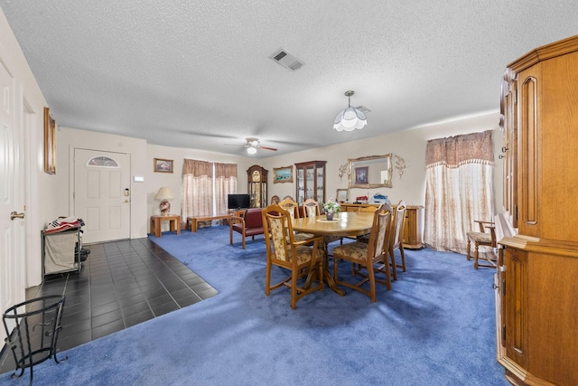 dining area featuring a textured ceiling, ceiling fan, and dark carpet