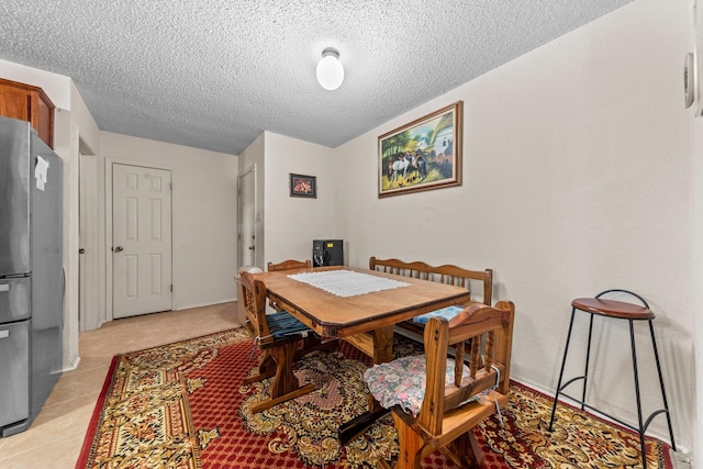 dining space with a textured ceiling and light tile patterned flooring