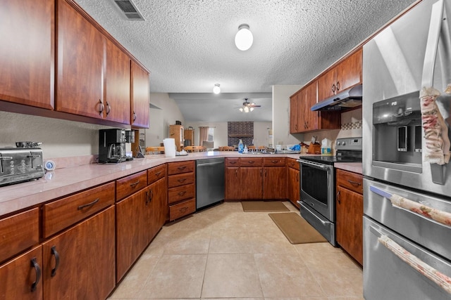 kitchen with light tile patterned floors, kitchen peninsula, ceiling fan, appliances with stainless steel finishes, and a textured ceiling