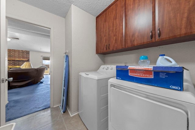 clothes washing area featuring light carpet, cabinets, a textured ceiling, and washing machine and dryer