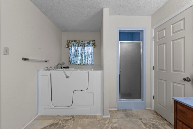 bathroom featuring vanity, independent shower and bath, washer / dryer, and a textured ceiling