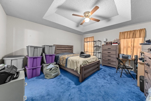 carpeted bedroom with a raised ceiling, ceiling fan, and a textured ceiling