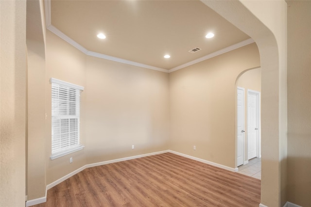 spare room featuring crown molding and light hardwood / wood-style flooring