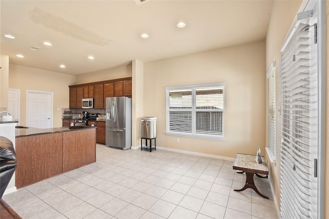 kitchen with sink, light tile patterned floors, stainless steel appliances, and kitchen peninsula