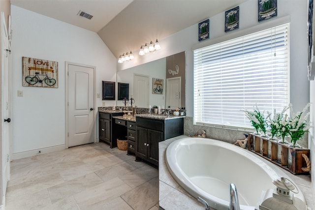 bathroom featuring vanity, a wealth of natural light, lofted ceiling, and a relaxing tiled tub