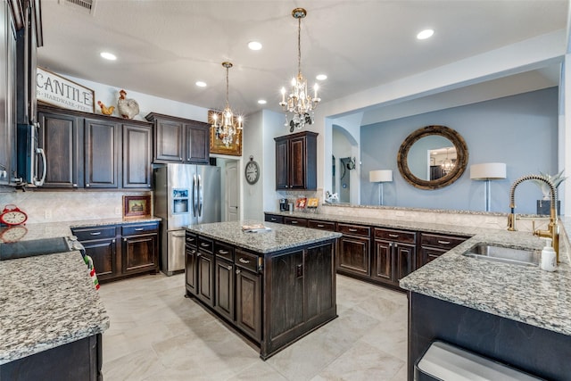 kitchen with dark brown cabinetry, a center island, appliances with stainless steel finishes, decorative light fixtures, and tasteful backsplash