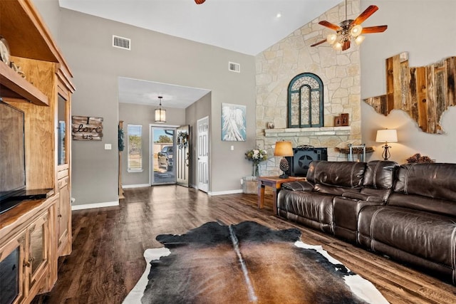 1536 Kings Ranch Rd, Bandera, TX 78003 - living room featuring high vaulted ceiling, dark wood-type flooring, ceiling fan, a stone fireplace, and baseboards