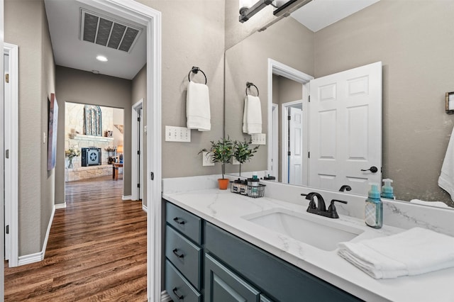 bathroom with vanity, a stone fireplace, and hardwood / wood-style floors