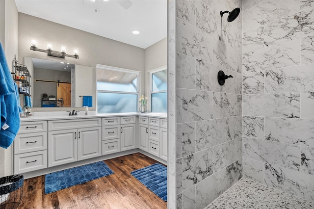 bathroom with wood-type flooring, tiled shower, and vanity