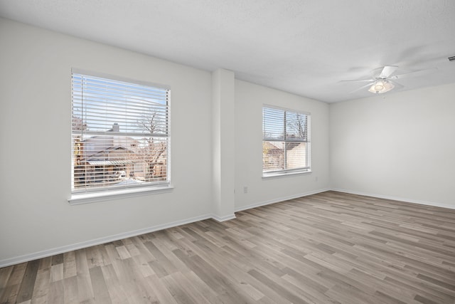 spare room featuring ceiling fan, a healthy amount of sunlight, and light hardwood / wood-style floors