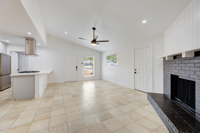 unfurnished living room featuring a brick fireplace, light tile patterned floors, lofted ceiling, and ceiling fan