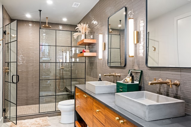 bathroom with tile patterned floors, vanity, tile walls, toilet, and a shower with shower door