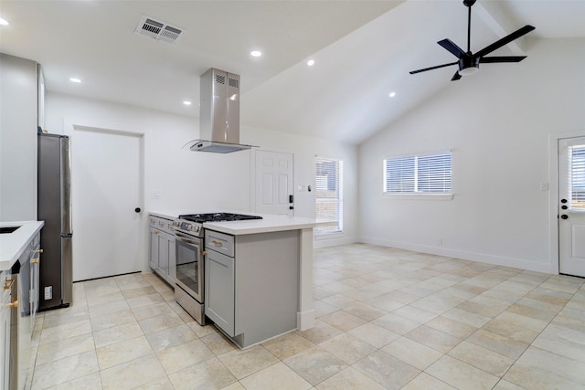 kitchen with island exhaust hood, appliances with stainless steel finishes, a healthy amount of sunlight, gray cabinetry, and lofted ceiling