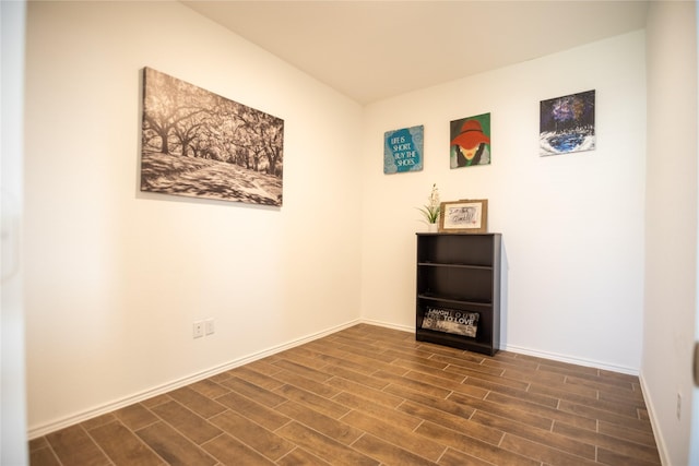 spare room with baseboards and dark wood-style flooring