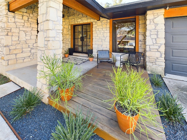 view of exterior entry featuring covered porch and a garage