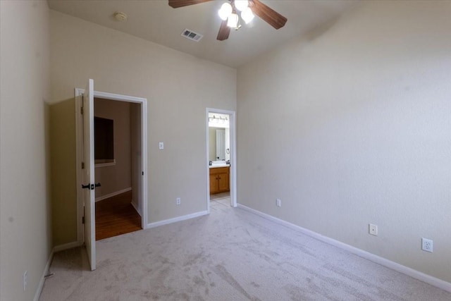 unfurnished bedroom featuring ceiling fan, ensuite bath, and light carpet