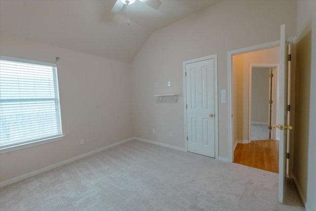 unfurnished bedroom featuring vaulted ceiling, light colored carpet, and ceiling fan