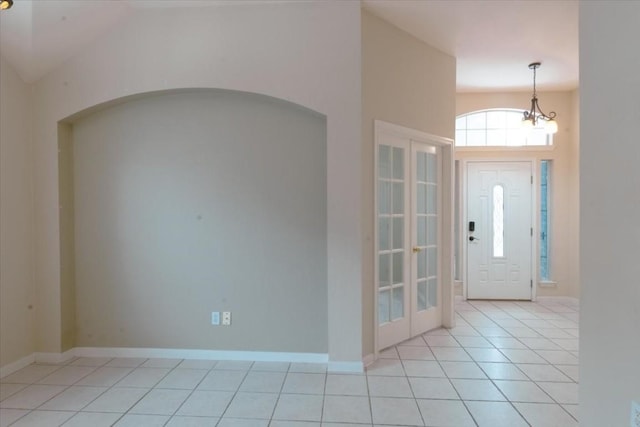 foyer featuring vaulted ceiling, a chandelier, and light tile patterned flooring