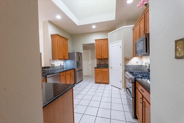 kitchen featuring light tile patterned flooring, stainless steel appliances, and dark stone countertops