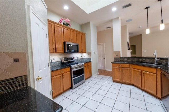 kitchen with pendant lighting, sink, appliances with stainless steel finishes, backsplash, and dark stone counters