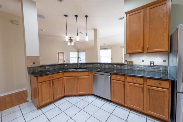 kitchen with sink, hanging light fixtures, dark stone counters, stainless steel appliances, and backsplash