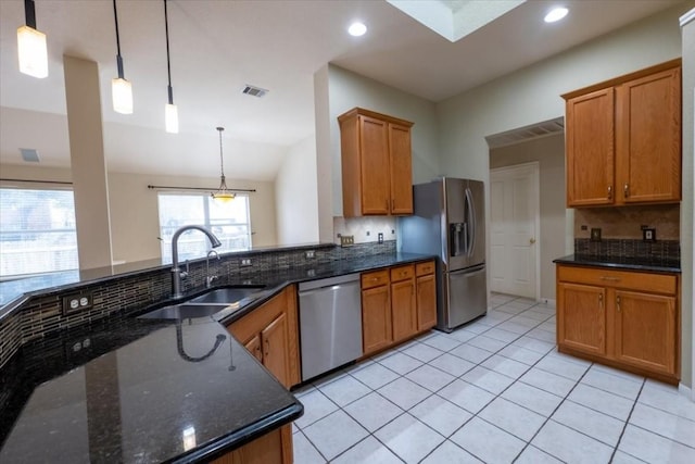 kitchen featuring stainless steel appliances, hanging light fixtures, sink, and dark stone counters