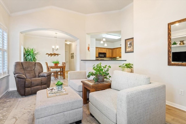 living room featuring a notable chandelier, ornamental molding, and light hardwood / wood-style floors