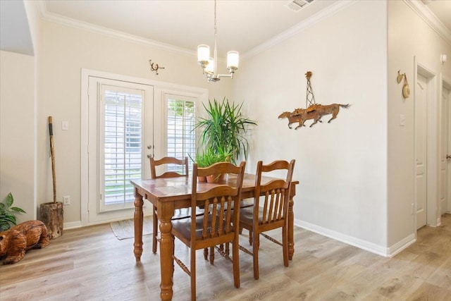 dining area featuring light wood-type flooring, an inviting chandelier, and crown molding