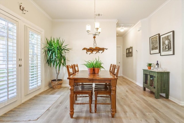 dining room featuring light hardwood / wood-style floors, crown molding, and a notable chandelier