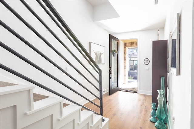 foyer featuring light wood-style floors, visible vents, stairs, and baseboards