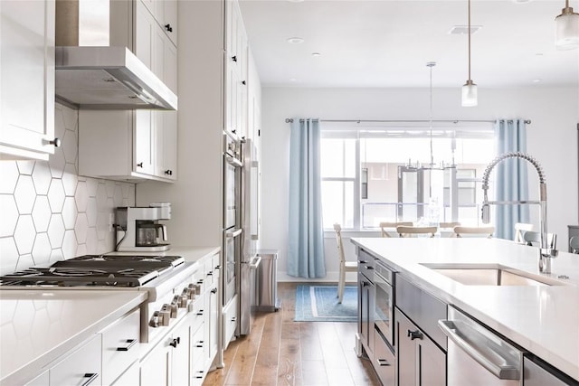 kitchen with wall chimney exhaust hood, light countertops, and white cabinetry