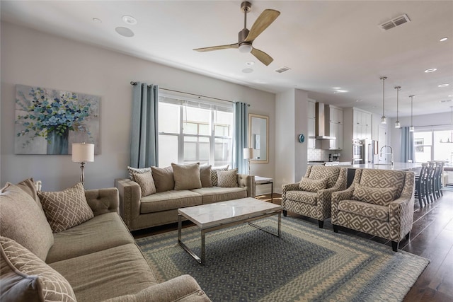 living room with ceiling fan, dark wood-type flooring, sink, and a healthy amount of sunlight