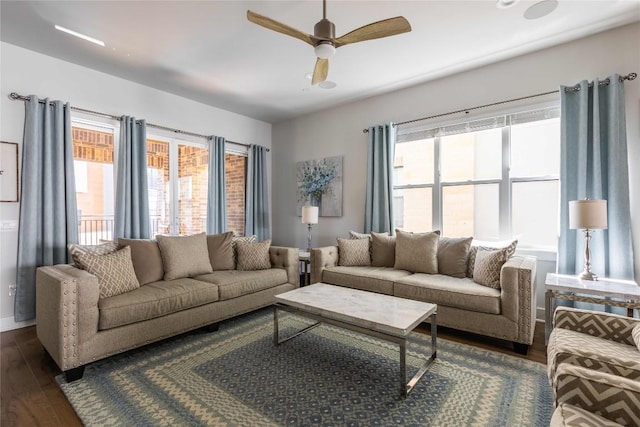 living area with dark wood-type flooring, plenty of natural light, and ceiling fan