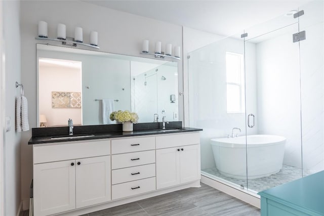 4007 Emory Peak Pass, Austin, TX 78731 - bathroom featuring a soaking tub, double vanity, a stall shower, and wood finished floors