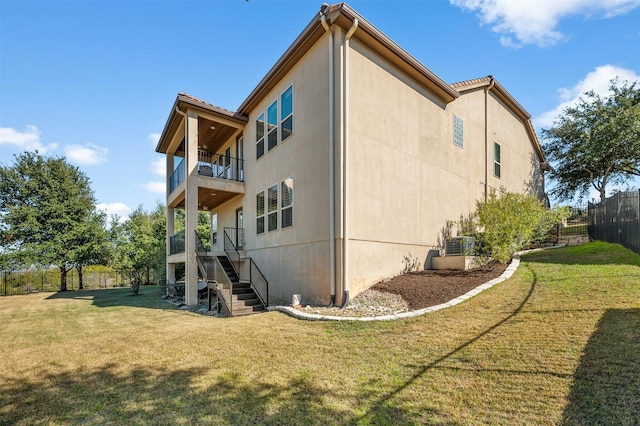 back of property featuring a balcony and a lawn