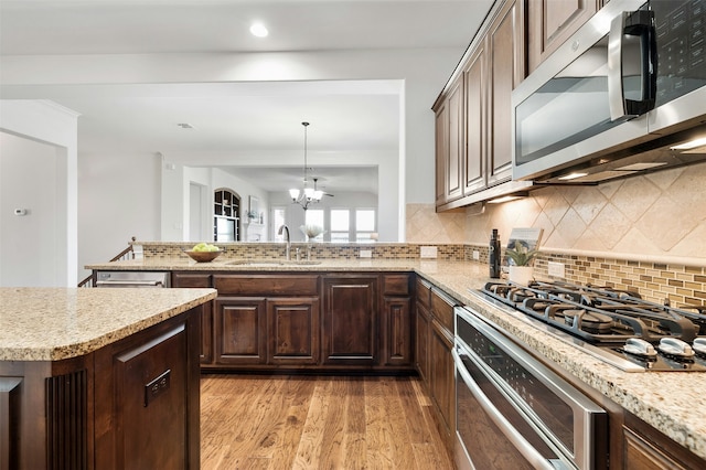 kitchen with hanging light fixtures, appliances with stainless steel finishes, sink, tasteful backsplash, and a chandelier