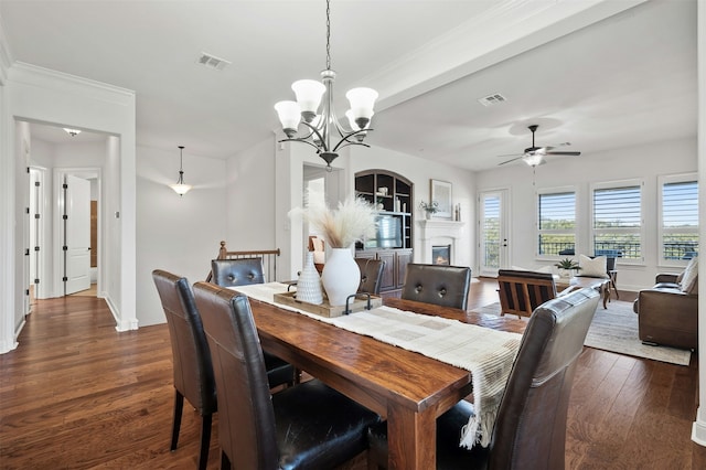 dining space featuring dark wood-type flooring, ceiling fan with notable chandelier, and beamed ceiling