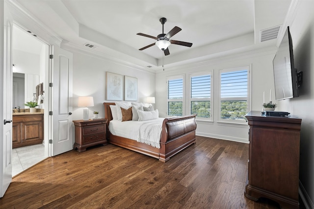 bedroom featuring ceiling fan, connected bathroom, dark hardwood / wood-style flooring, and a raised ceiling