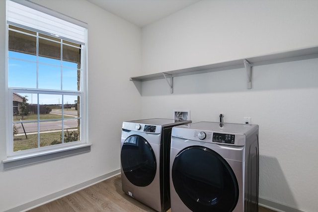 laundry area with light hardwood / wood-style flooring and washer and clothes dryer