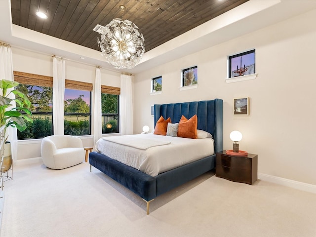 carpeted bedroom featuring a notable chandelier, wood ceiling, and a tray ceiling