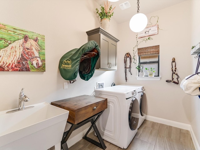 laundry room with cabinets, sink, washing machine and clothes dryer, and light hardwood / wood-style floors