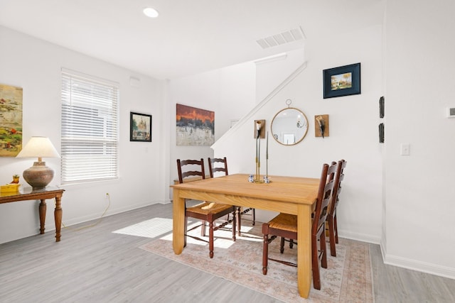 dining space with light wood finished floors, baseboards, and visible vents