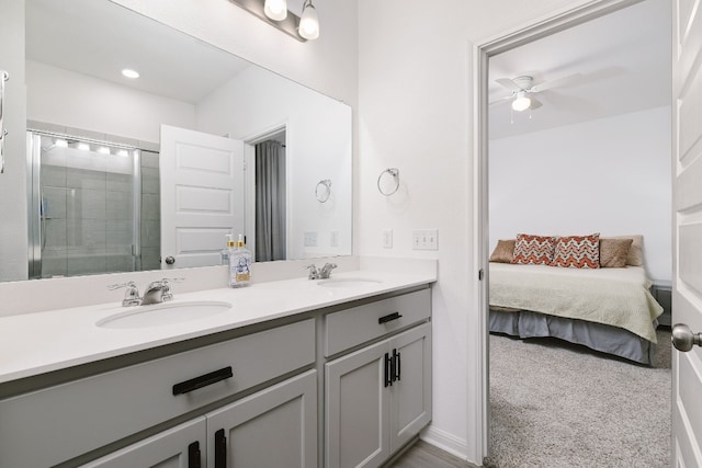 ensuite bathroom with double vanity, ceiling fan, a sink, and tiled shower