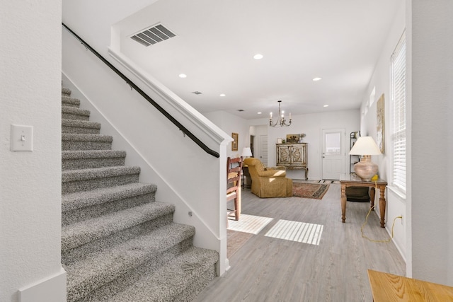 stairs with a chandelier, wood finished floors, visible vents, and recessed lighting