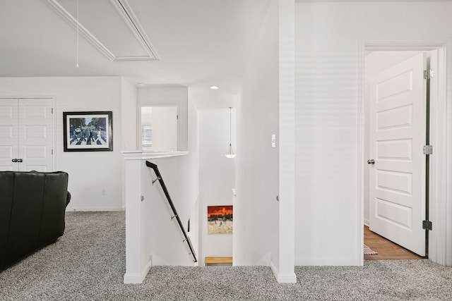 corridor featuring carpet, attic access, baseboards, and an upstairs landing