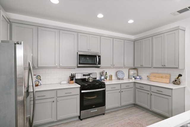 kitchen with stainless steel appliances, decorative backsplash, visible vents, and gray cabinetry