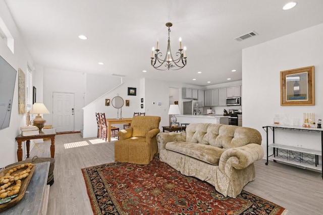 living area with light wood finished floors, recessed lighting, visible vents, and an inviting chandelier