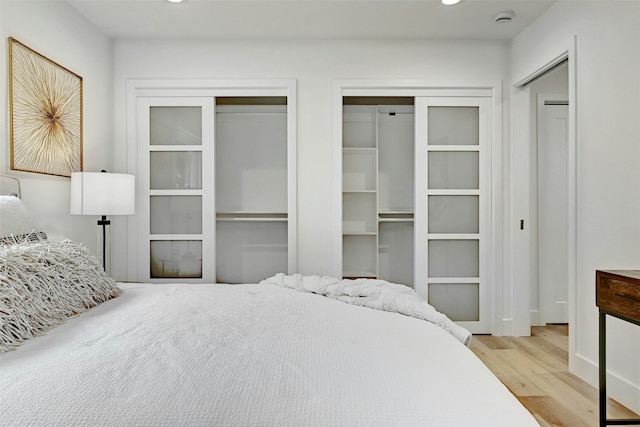 bedroom with two closets and light wood-type flooring