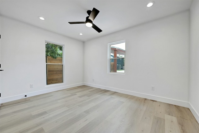 empty room with ceiling fan, plenty of natural light, and light hardwood / wood-style flooring